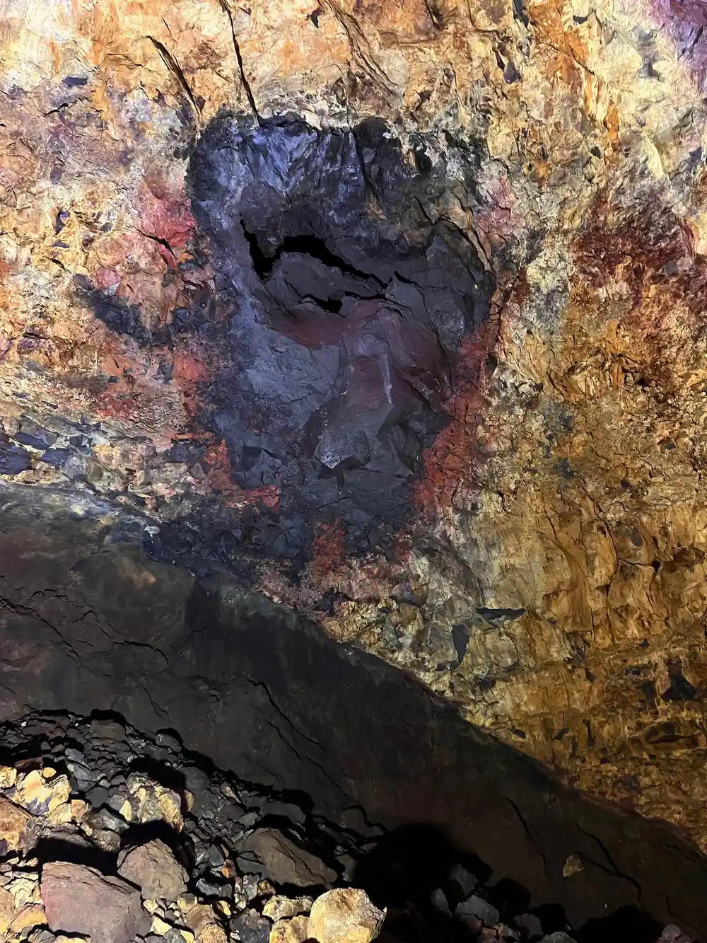 The chamber roof in rust and grey over the boulder floor