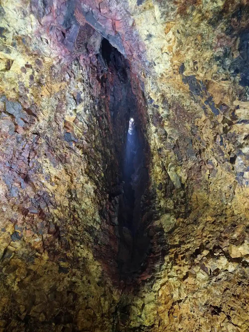 A deep blue-black fissure splitting the gold wall