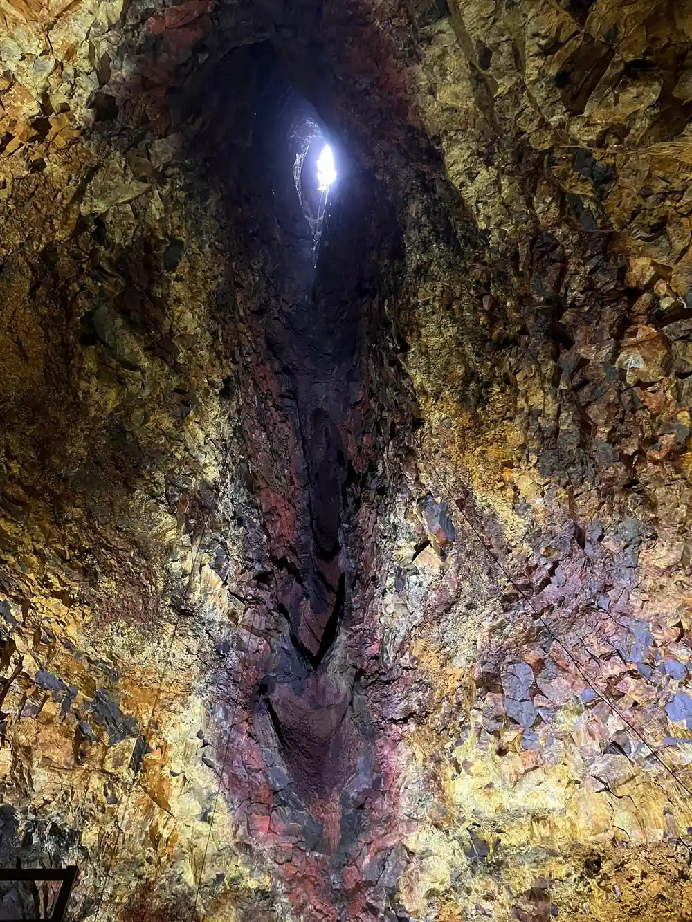 A lamp high on the wall above a dark cleft