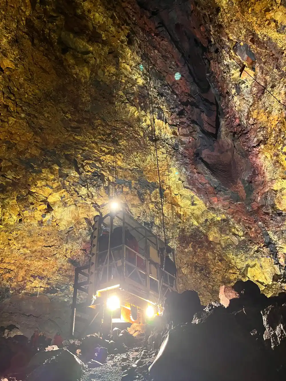 The lift platform seen from the floor, lit, part way down the shaft