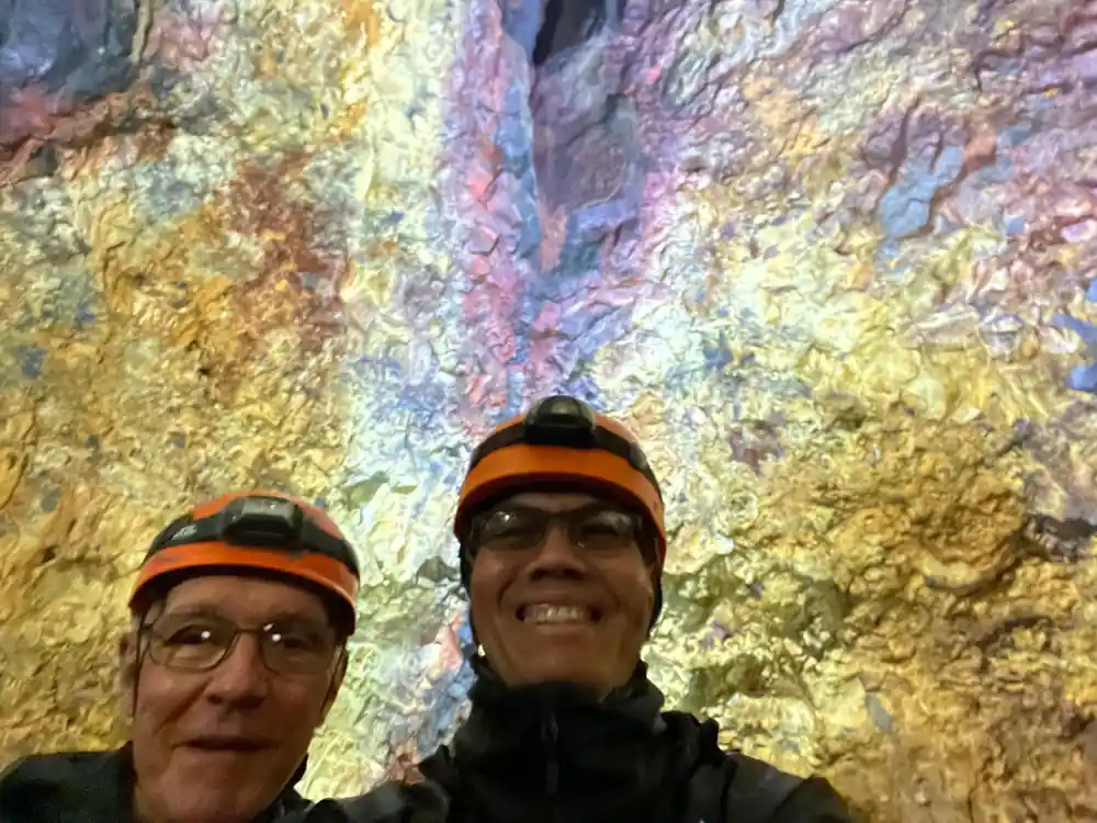 Two visitors against a wall of pale gold and violet streaks