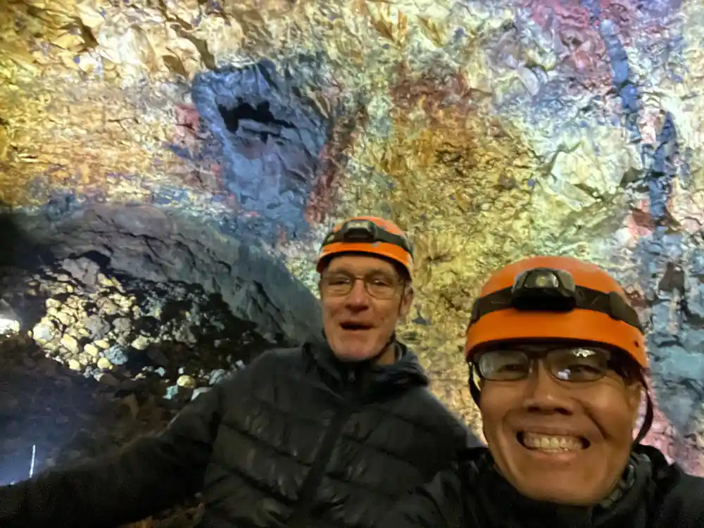 Two visitors in helmets grinning under the coloured chamber roof